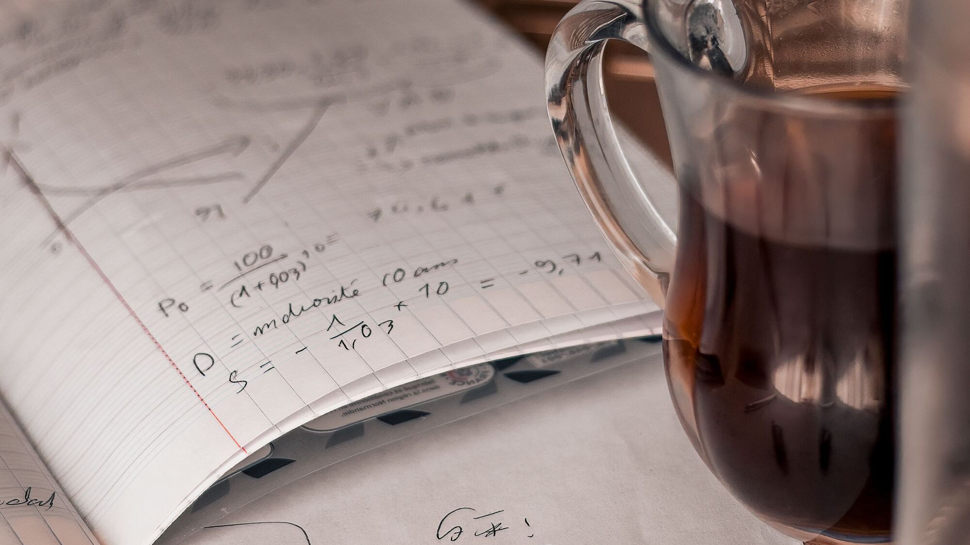 Coffee cup beside a workbook of handwritten present-value calculations